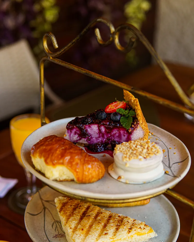 Suporte de três andares com croissant, torta de frutas vermelhas e torrada