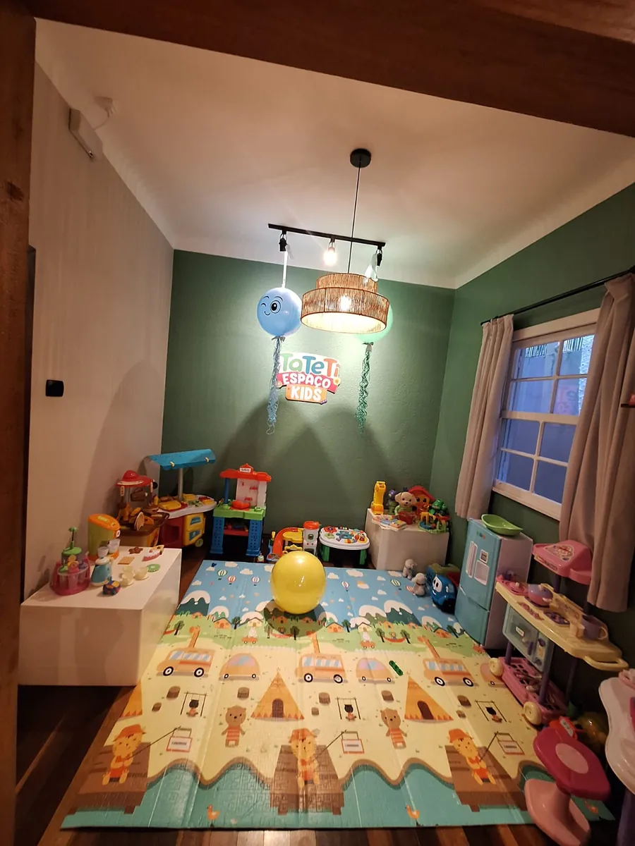 Outro ângulo do Espaço Kids, com o tapete de atividades, a janela e os brinquedos organizados